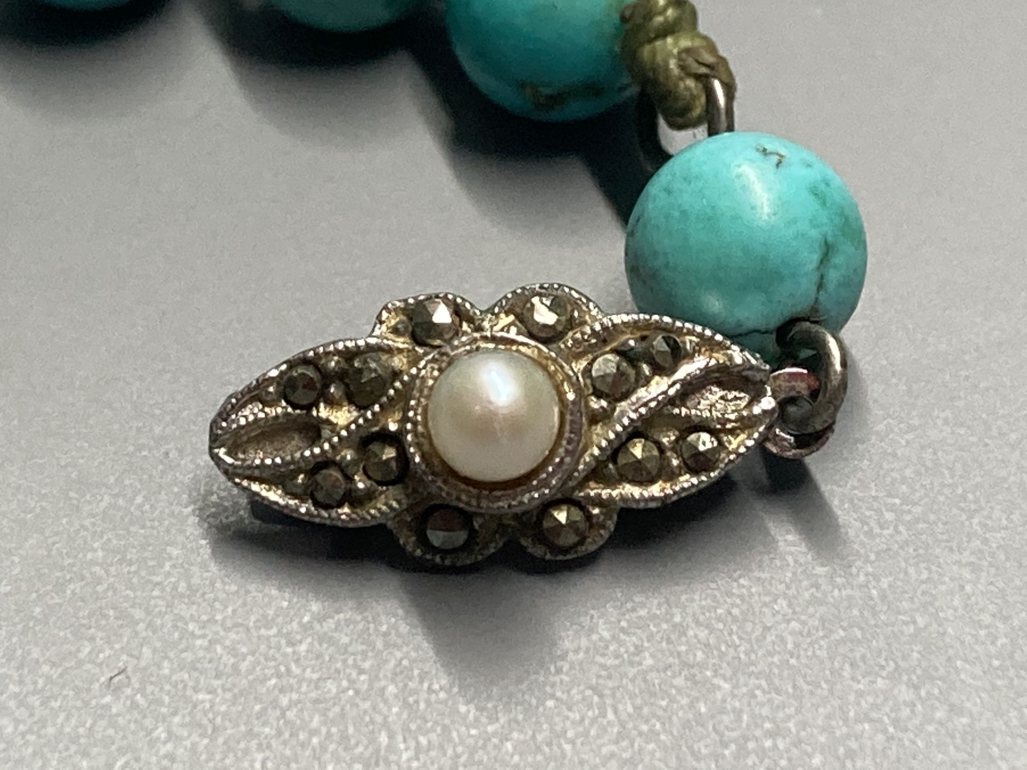 A continental graduated turquoise bead necklace, with marcasite and cultured pearl set white metal clasp, 57cm, gross 73 grams.